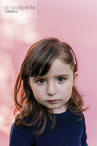 Porträt eines traurigen kleinen Mädchens vor rosa Hintergrund