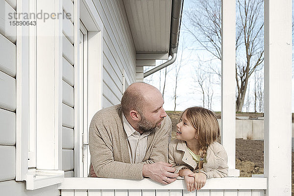 Vater und seine lächelnde Tochter auf der Veranda ihres Hauses