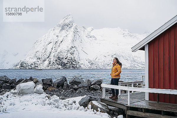 Tourist steht an einer Hütte an der Küste  Lofoten  Norwegen