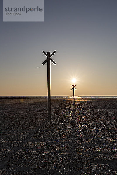 Dänemark  Romo  Silhouetten von Entfernungsmarkierungen am Küstenstrand bei Sonnenuntergang
