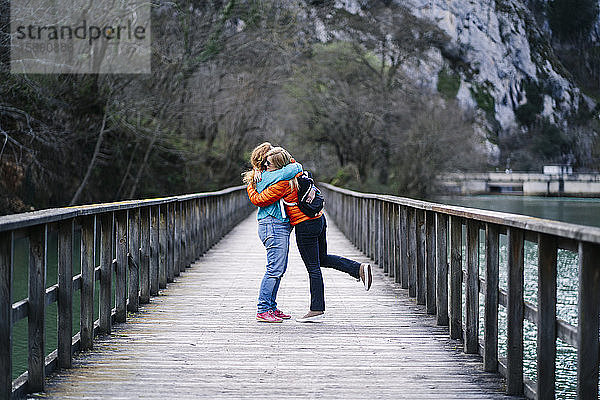 Zwei glückliche Frauen stehen auf der Strandpromenade und umarmen sich  Valdemurio-Stausee  Asturien  Spanien