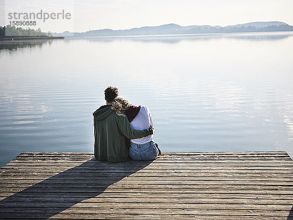 Romantisches Paar sitzt auf einem Steg am See