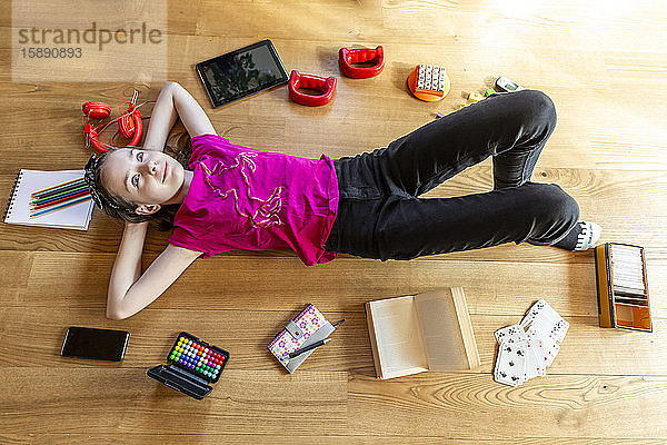 Mädchen auf dem Boden liegend  mit geschlossenen Augen  umgeben von Spielgeräten