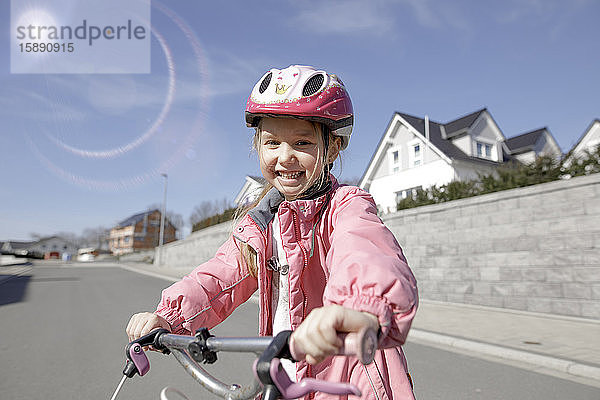 Porträt eines glücklichen kleinen Mädchens mit Fahrrad in einem Wohngebiet