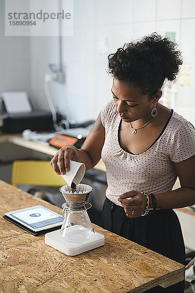 Frau  die in einer Kaffeerösterei arbeitet und frischen Filterkaffee zubereitet