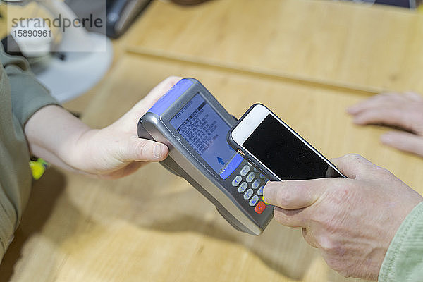Kunde bezahlt kontaktlos mit Smartphone in einem Geschäft