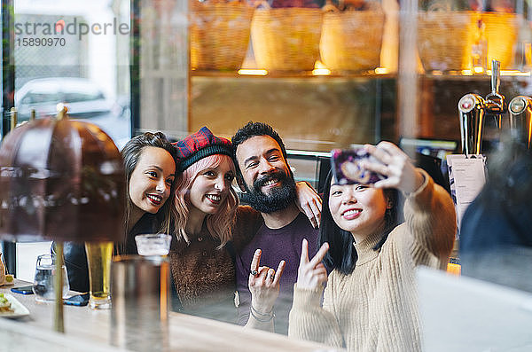 Freunde treffen sich in einer angesagten Bar und nehmen sich selbst ein Smartphone