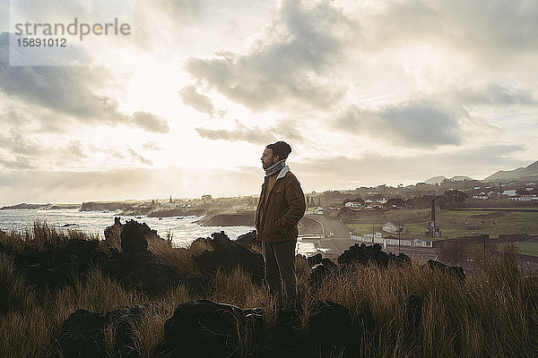 Mann steht in wilder Landschaft an der Küste  Insel Sao Miguel  Azoren  Portugal