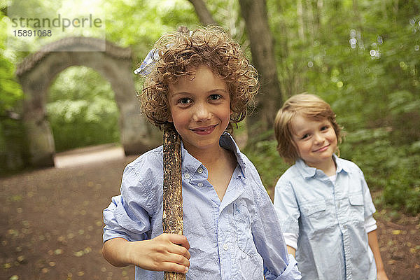 Bildnis eines Jungen mit Holzstock und Freund im Wald