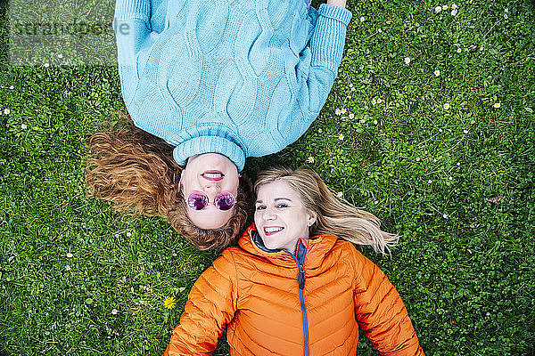 Porträt von zwei glücklichen Freunden auf einer Wiese liegend
