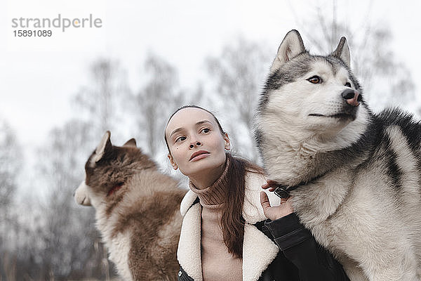 Porträt einer Frau mit zwei Huskies  die etwas beobachten