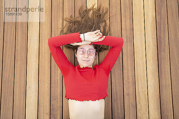 Porträt einer attraktiven jungen Frau  die auf einer Holzterrasse liegt