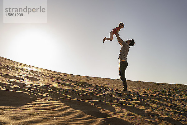 Vater spielt mit der Tochter in einer Sanddüne bei Sonnenuntergang  Gran Canaria  Spanien