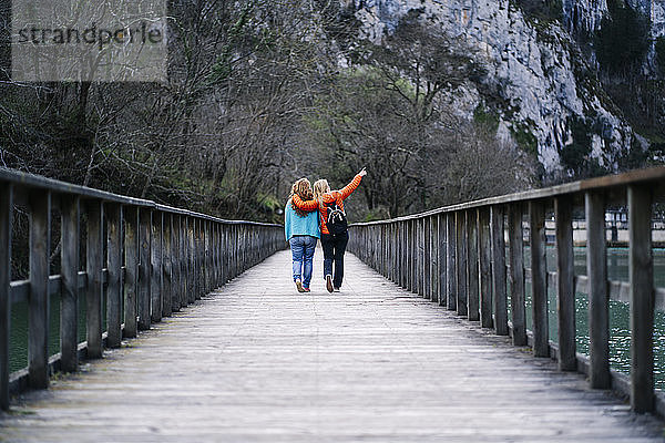 Rückansicht von zwei besten Freunden  die Seite an Seite auf einer Strandpromenade spazieren gehen  Valdemurio-Stausee  Asturien  Spanien