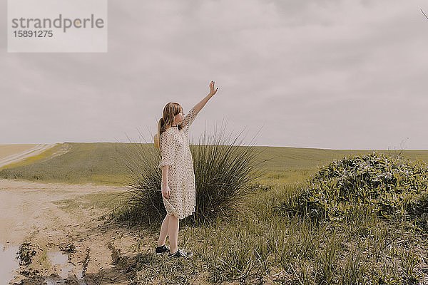 Frau in Vintage-Kleid allein auf einem abgelegenen Feld auf dem Land
