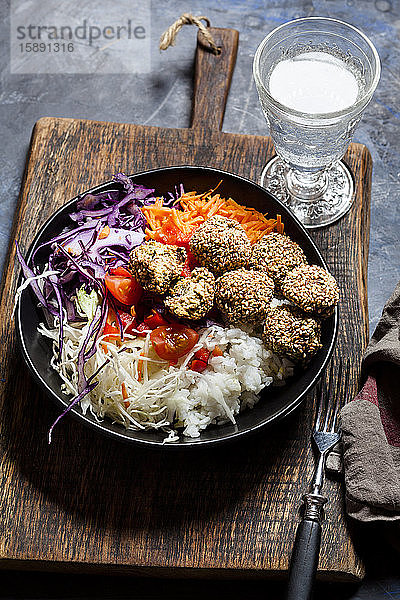 Schüssel mit verzehrfertigem Salat mit Weiss- und Rotkohl  Karotten  Reis und Spinatfalafel