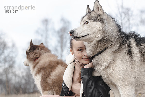 Porträt einer lächelnden Frau mit ihren Huskies