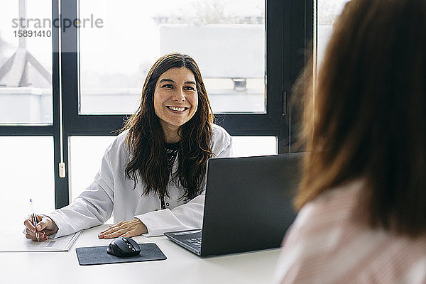 Lächelnder Arzt im Gespräch mit Patient in der medizinischen Praxis