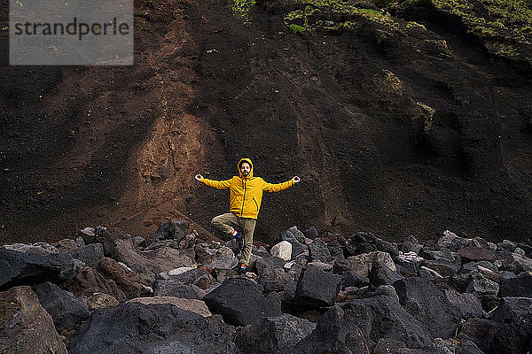 Mann steht in Yoga-Pose inmitten von Vulkangestein  Sao-Miguel-Insel  Azoren  Portugal