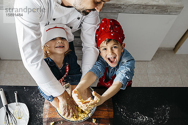 Porträt von glücklichen Kindern  die mit dem Vater zu Hause in der Küche Teig zubereiten