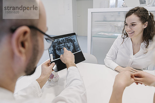 Zahnarzt spricht mit dem Patienten über Röntgenergebnisse
