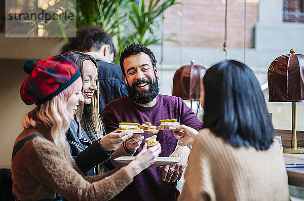 Freunde treffen sich in einer trendigen Bar und teilen sich die Vorspeisen