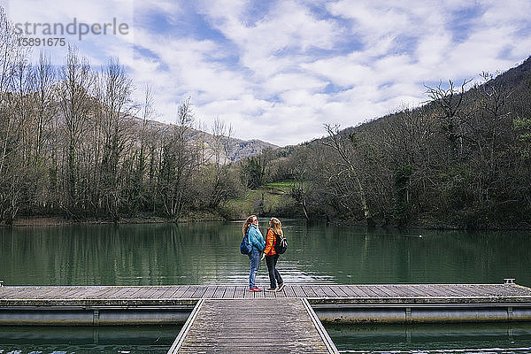 Zwei glückliche Frauen mit Rucksäcken stehen am Steg  Valdemurio-Stausee  Asturien  Spanien