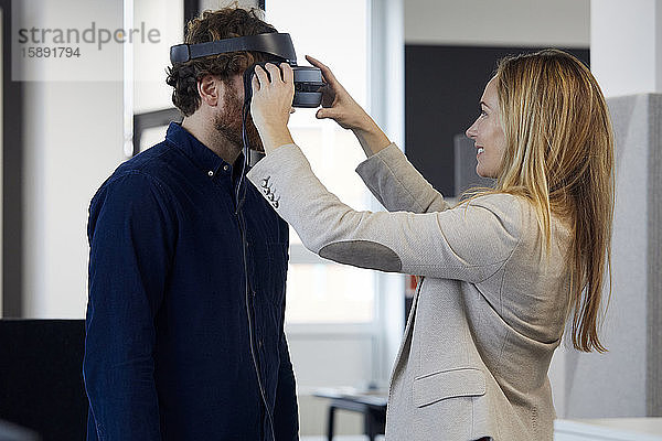 Geschäftsfrau setzt VR-Brille auf Geschäftsmann im Amt auf