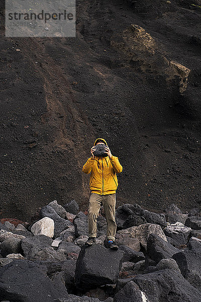 Mann steht inmitten von Vulkangestein  das sein Gesicht bedeckt  Insel Sao Miguel  Azoren  Portugal