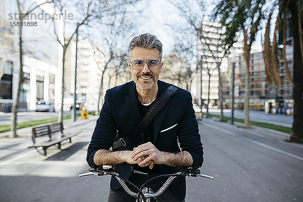 Porträt eines grauhaarigen Geschäftsmannes mit Fahrrad in der Stadt
