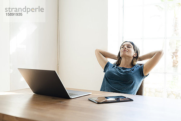 Junge Frau mit Laptop im Home-Office macht eine Pause