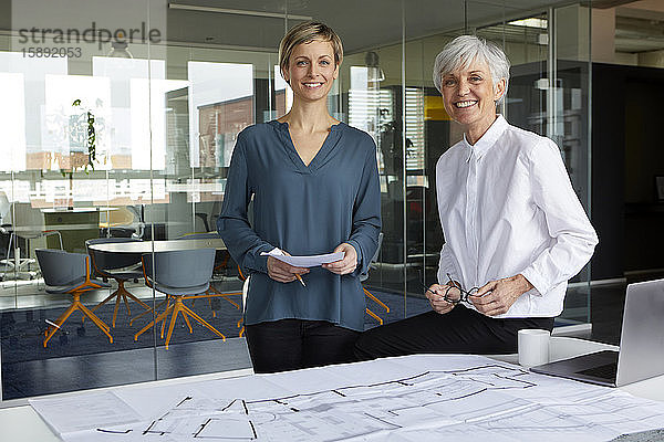 Porträt von zwei selbstbewussten Geschäftsfrauen mit Bauplan im Amt