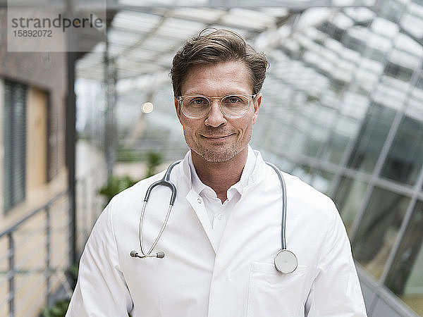 Porträt eines Arztes mit Stethoskop  stehend im Atrium