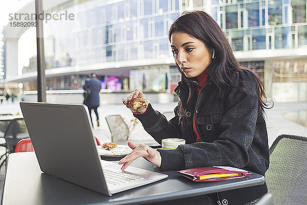 Frau mit Laptop beim Frühstück in einem Café