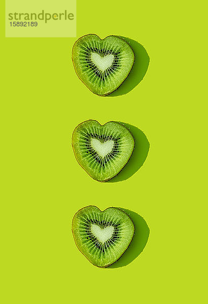 Herzförmige Kiwi-Fruchtscheiben Muster auf grünem Hintergrund