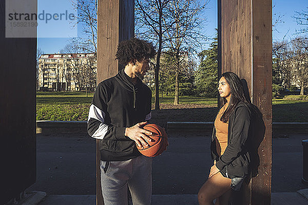 Junger Mann und Frau treffen sich am Basketballplatz