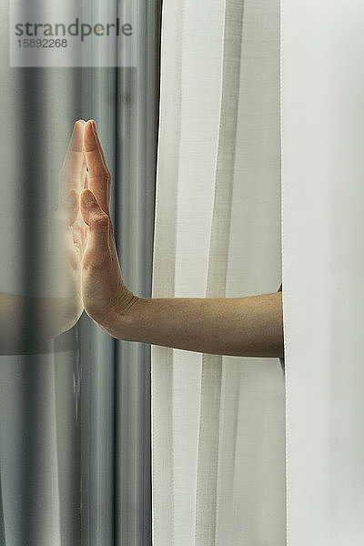 Hand einer Frau  die eine Fensterscheibe berührt