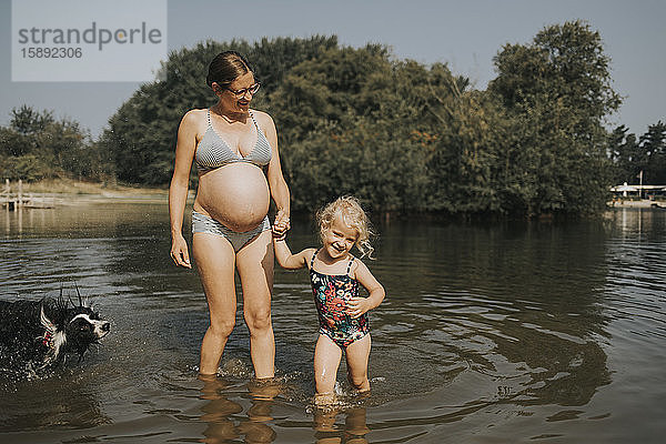 Niederlande  Schiermonnikoog  schwangere Mutter mit Tochter und Border Collie in einem See