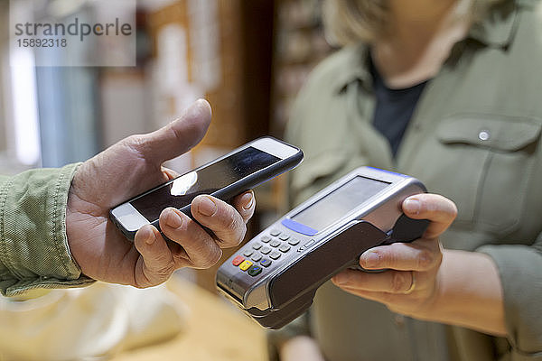 Kunde bezahlt kontaktlos mit Smartphone in einem Geschäft