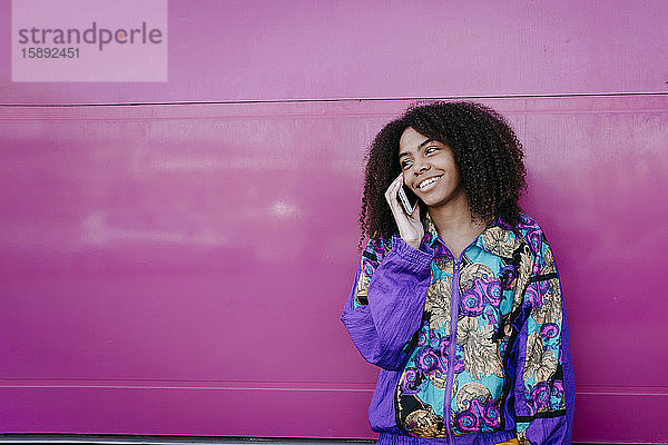 Lächelnde Frau beim Telefonieren  rosa Wand im Hintergrund