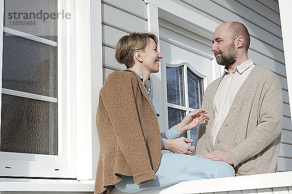 Glückliches Paar im Gespräch auf der Veranda ihres Hauses