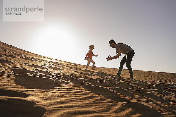 Vater und Tochter spielen bei Sonnenuntergang in einer Sanddüne  Gran Canaria  Spanien