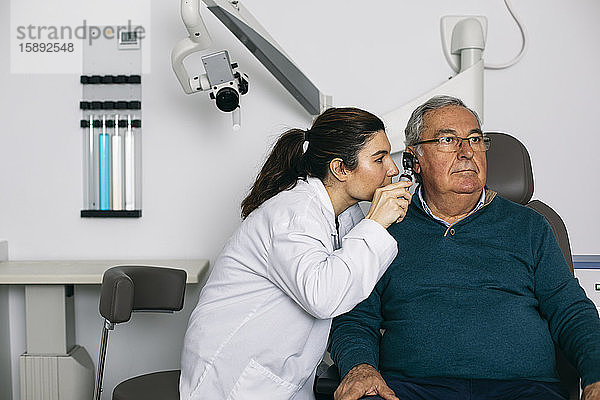 HNO-Arzt untersucht das Ohr eines älteren Mannes mit einem Otoskop