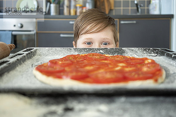 Junge mit roher Pizza auf Backblech