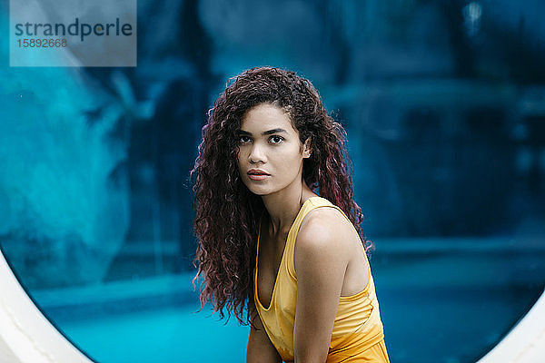 Bildnis einer jungen Frau mit Locken vor blauem Hintergrund