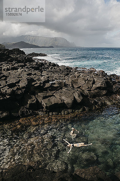 Schrägansicht auf Freunde  die im Queen's Bath auf Kauai  Hawaii-Inseln  USA  schwimmen