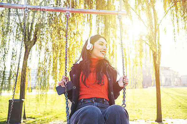 Schöne Frau sitzt auf einer Schaukel und hört Musik