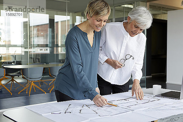 Zwei Geschäftsfrauen arbeiten gemeinsam am Bauplan im Amt