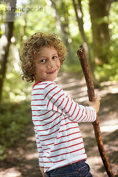 Bildnis eines Jungen mit Holzstock beim Waldspaziergang