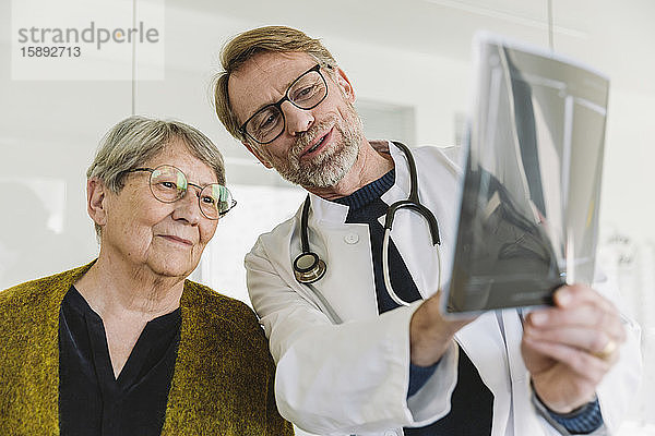 Arzt bespricht Röntgenbild mit älterem Patienten